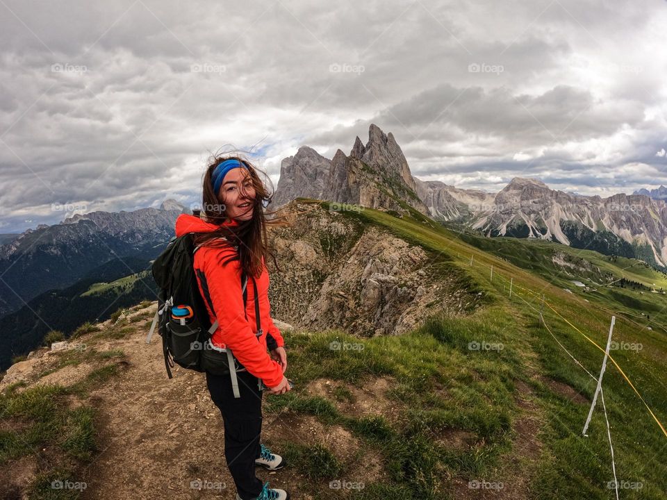 Woman while on a hike in the Dolomites, with Seceda mountain in the background.