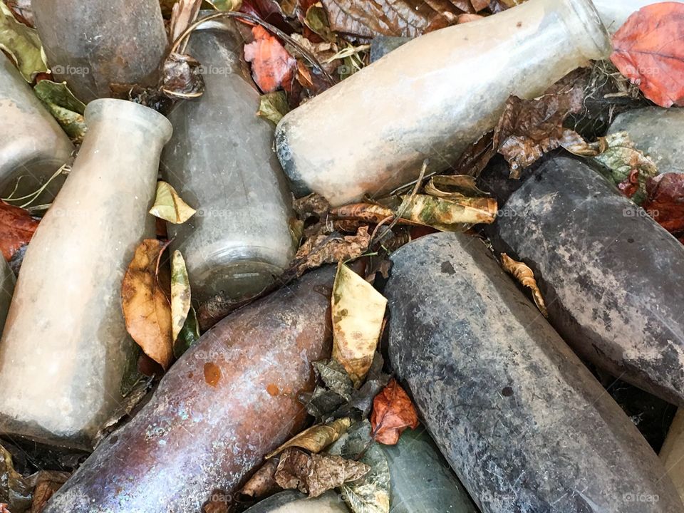 Background image collection of old dirty grungy vintage and antique bottles laying on their sides 