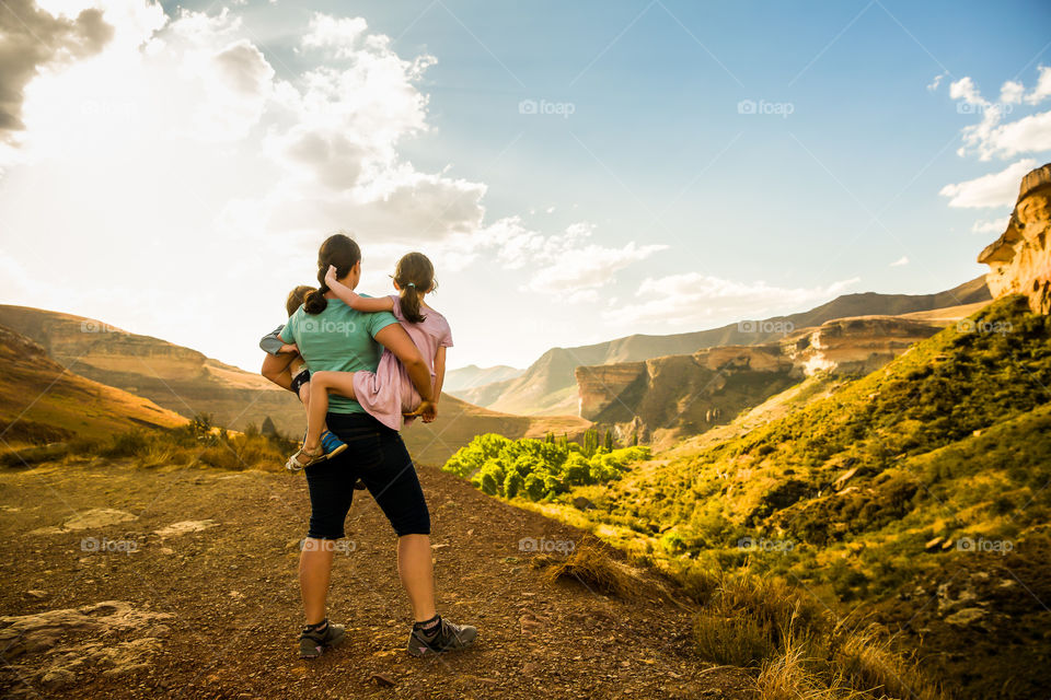 Golden  hour photography! Image of mom holding her two kids overlooking Golden Gate sandstone mountains in Africa.