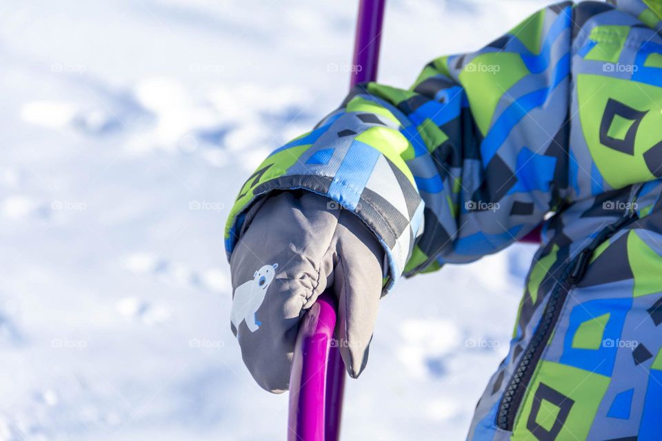 A child in winter in winter jackets, pants, a hat and boots on white snow on the street and in the park in nature plays winter fun and sleds.
