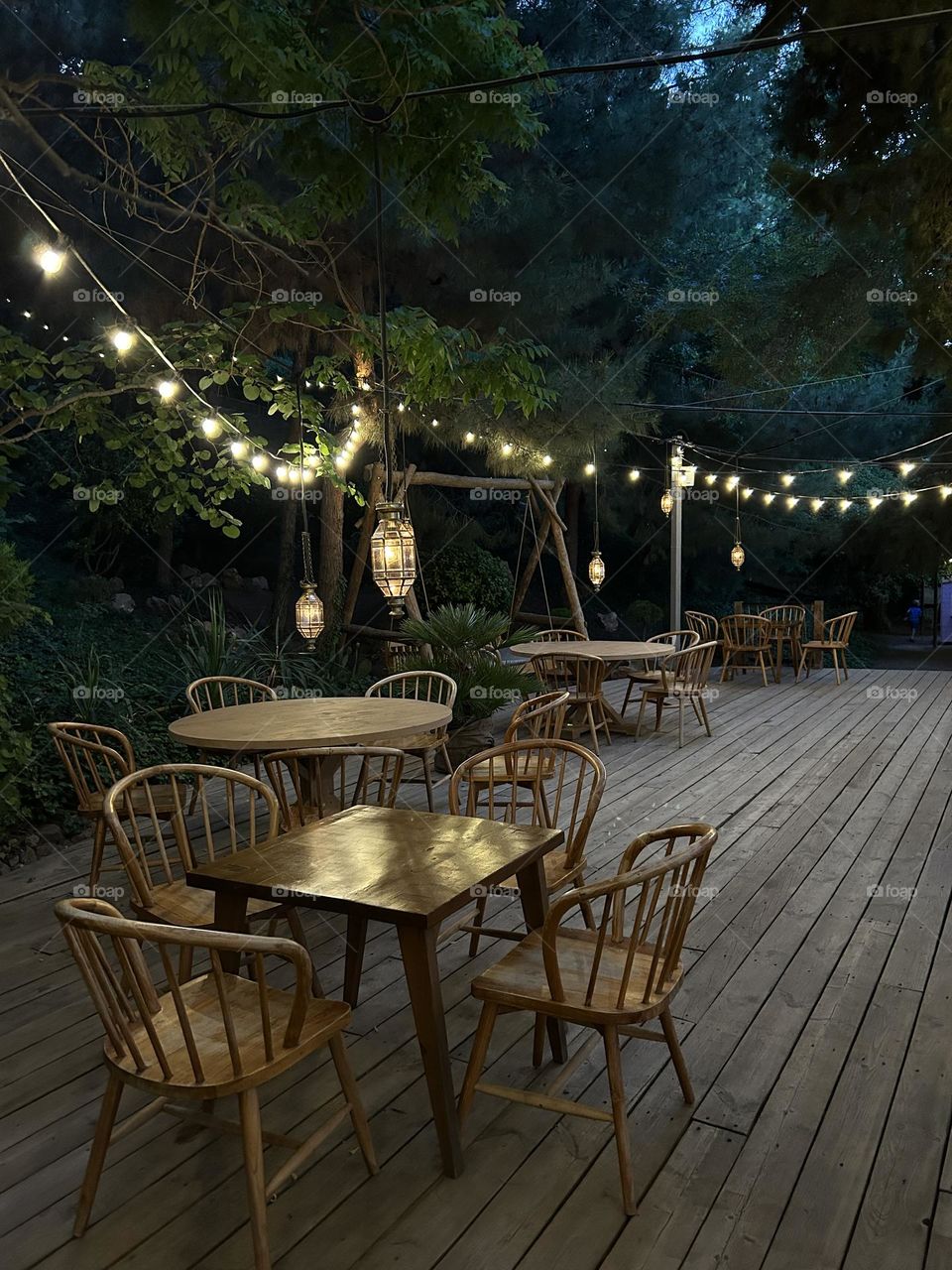 Authentic street cafe with electric garland lights in garden at summer night 