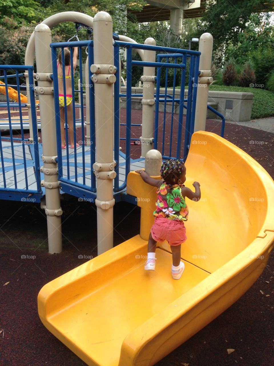 Great Day For A Slide. Toddler girl on a big yellow slide at the playground 
