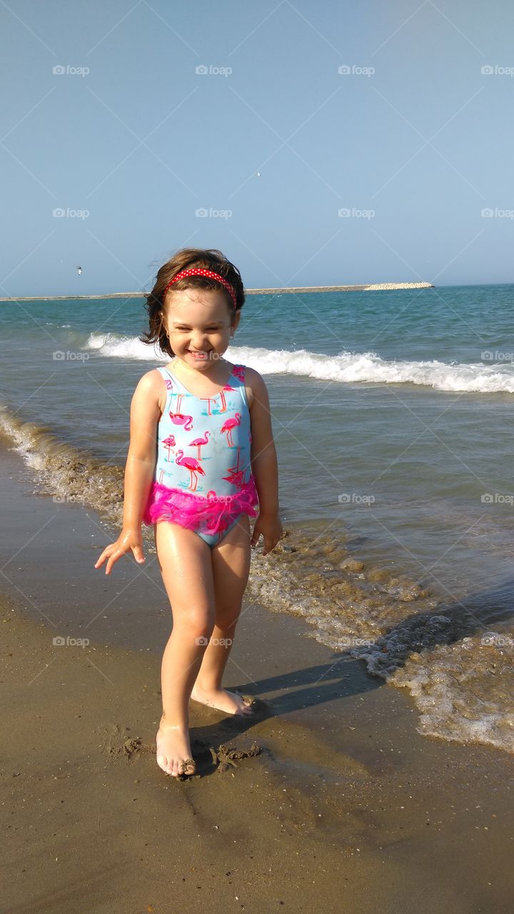 Happy little girl standing at beach