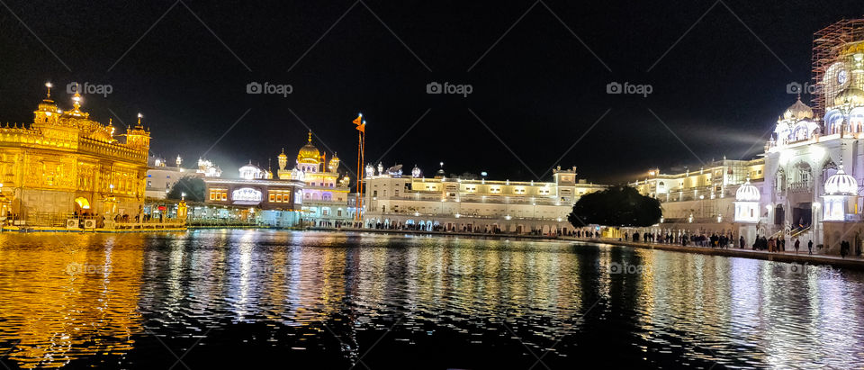 Wide angle view of a Golden temple reflecting it's building in water
