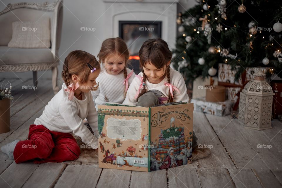 Little sisters near Christmas tree at home