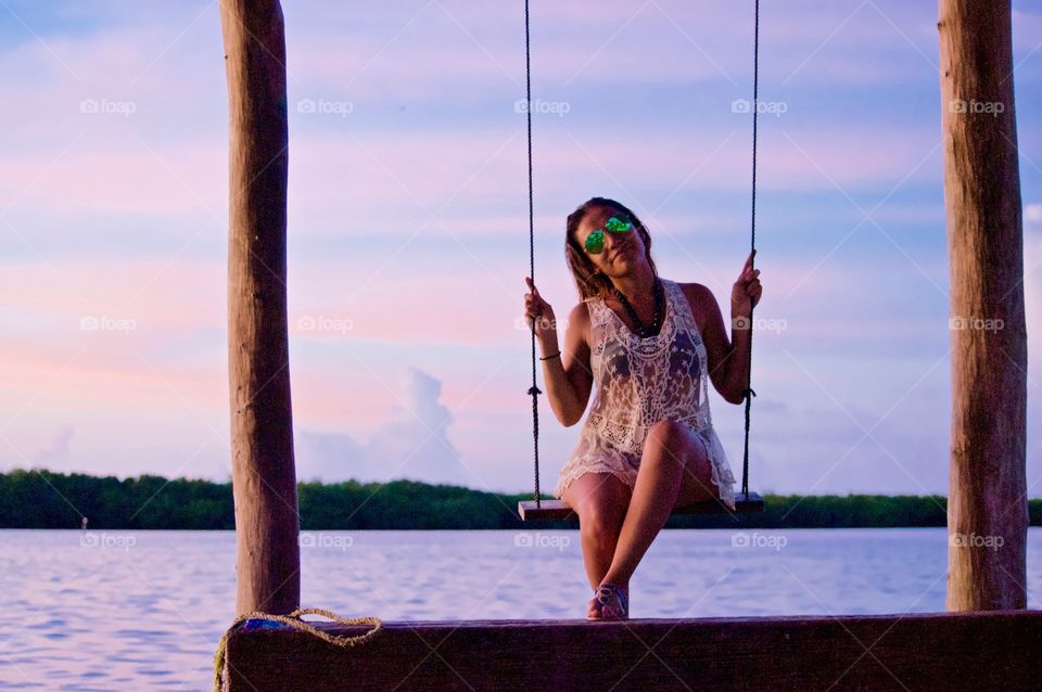Woman sitting on swing during sunset