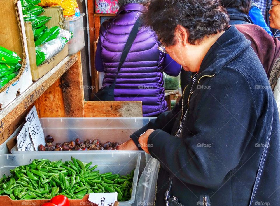 Woman Buying Vegetables At A Chinese Street Market. Shopping For Spices In A Chinese Market
