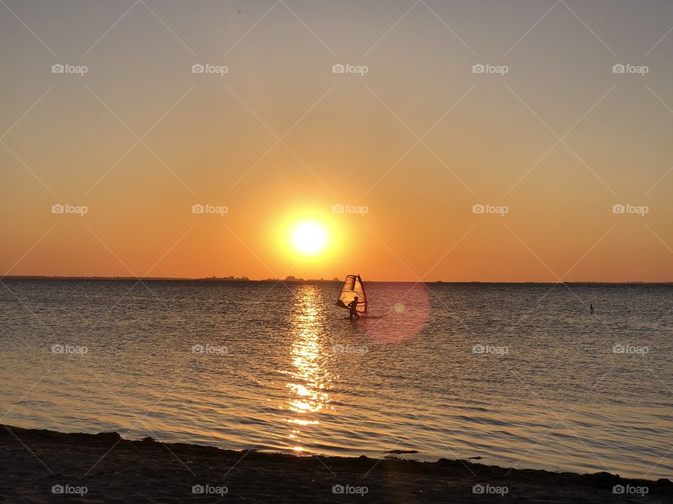 Sunset at the beach with a windsurfer in the water