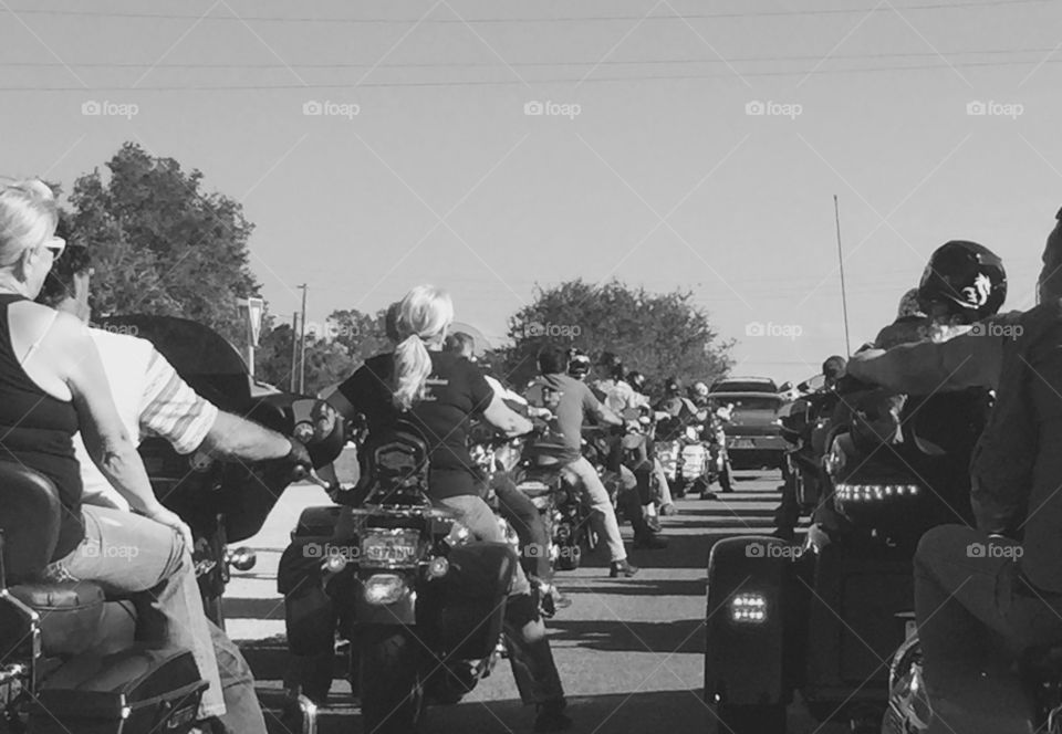 Motorcyclists in Daytona Beach and Ormond Beach Florida during Biketoberfest biker festival. Monochrome black and white photo, Rear view with men and women riding Harley Davidson, Honda, BMW motorbikes, trikes and 3-wheelers. Bikers wait at light with line of cars, views from behind. 