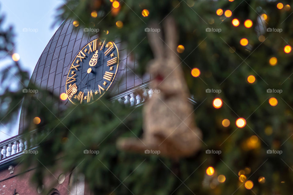 Christmas decorations and lights. In the background clock in church tower,