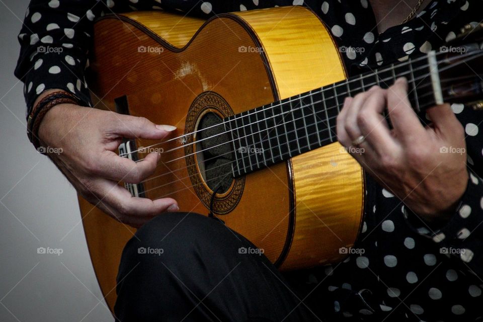 Man is playing Hispanic guitar