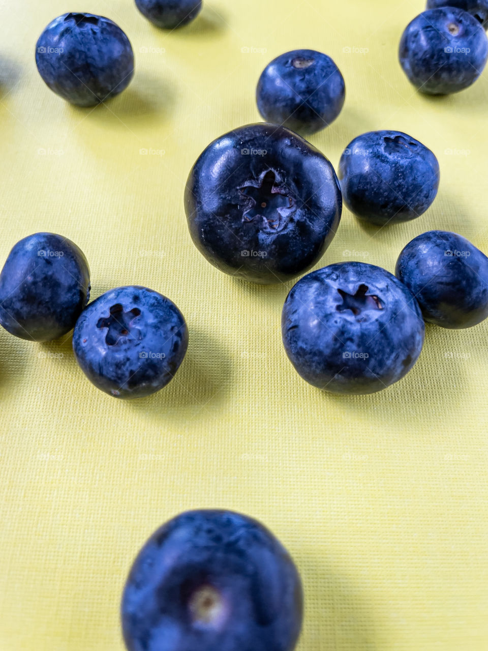 Up close look at fresh blueberries on yellow background 
