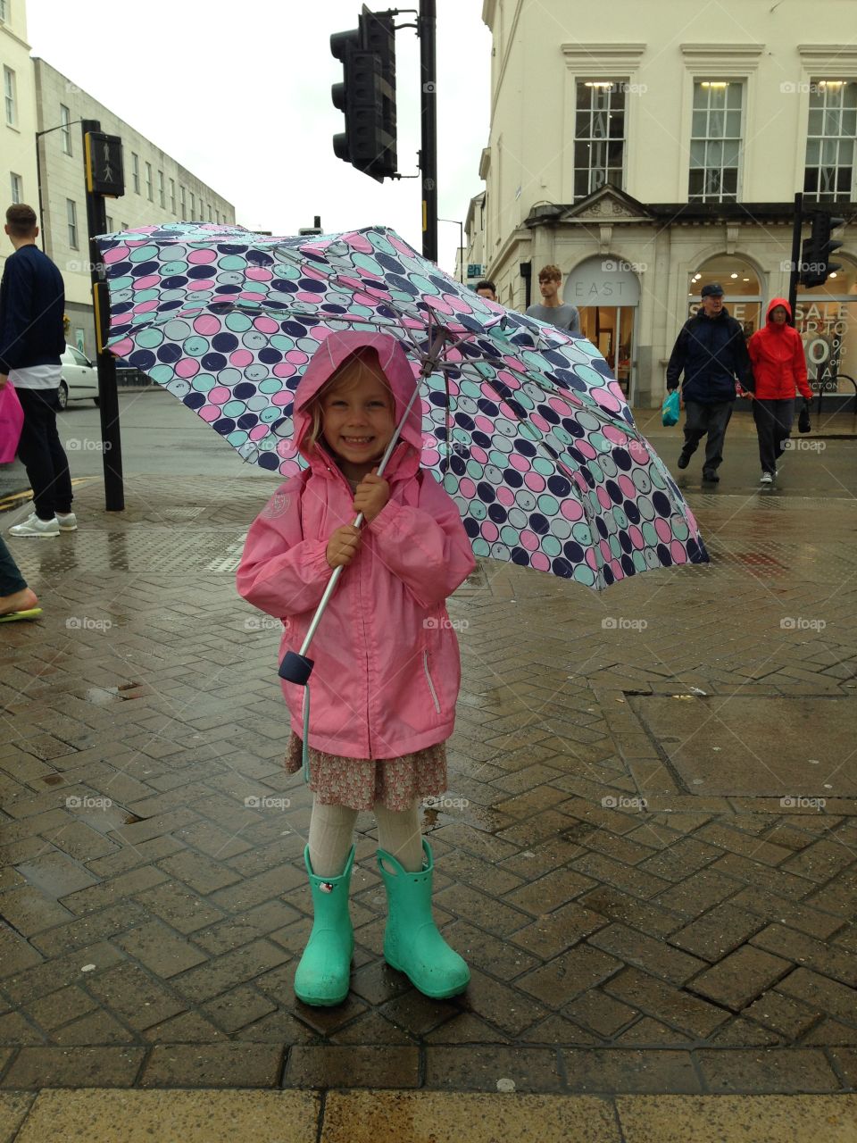 A happy girl in the rain under the umbrella