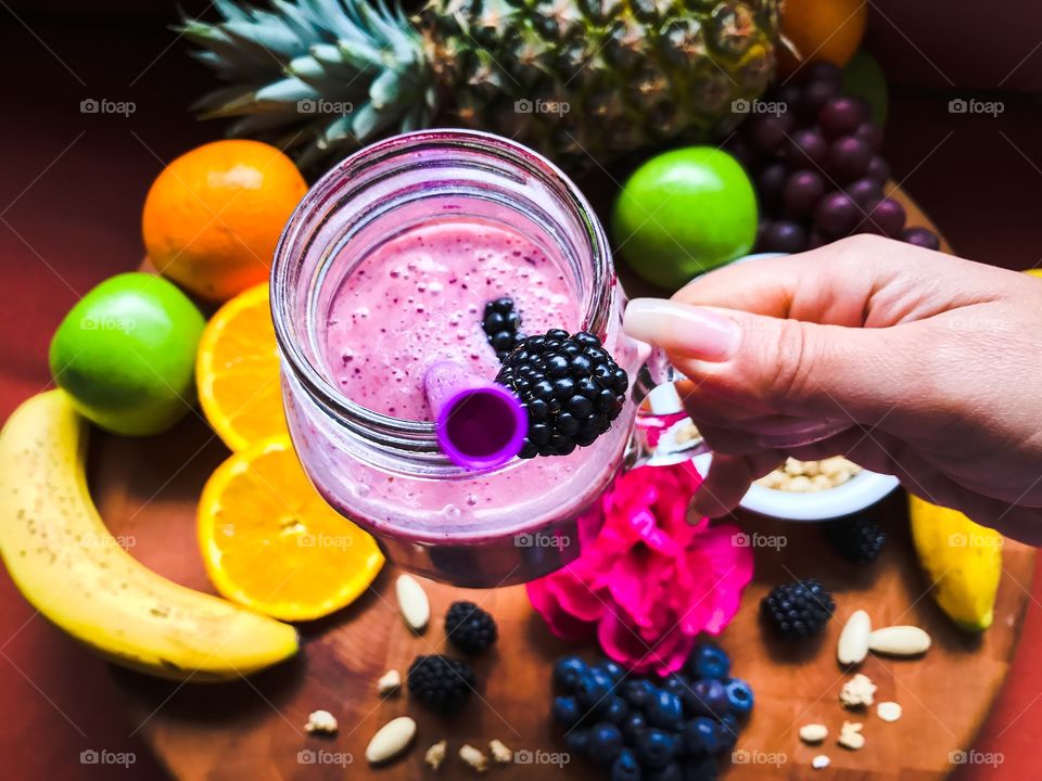 Person holding glass of fruit smoothie