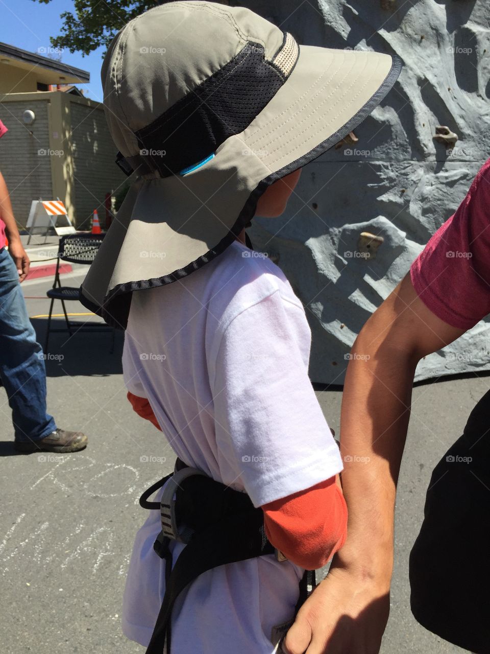 Kid in rock climbing harness, getting ready to conquer the rock wall