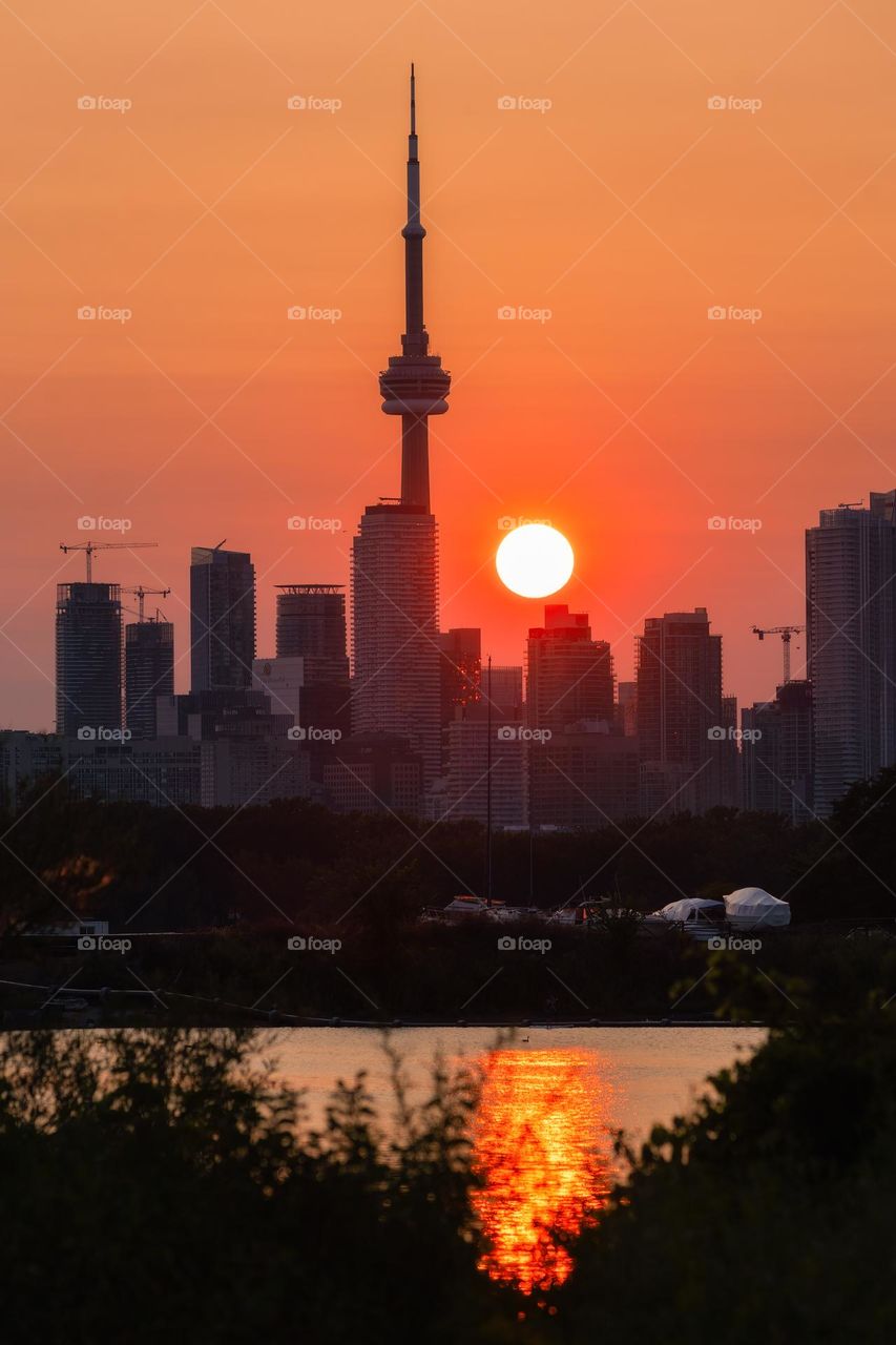 Hazy vibrant sunset over the Toronto skyline, with the sun setting next to the CN Tower