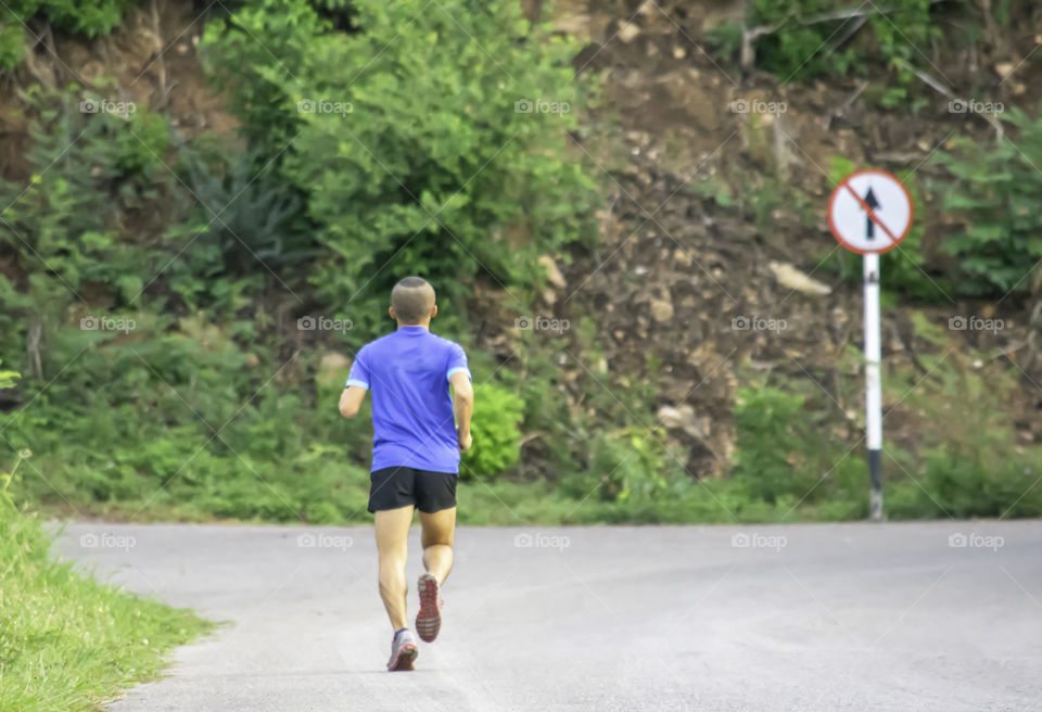 The men are running on the road Background light poles and trees.