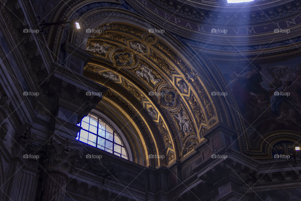 A portrait of a roman window with some light coming from an opening from above in a roman catholic church. The windows are half elipses.