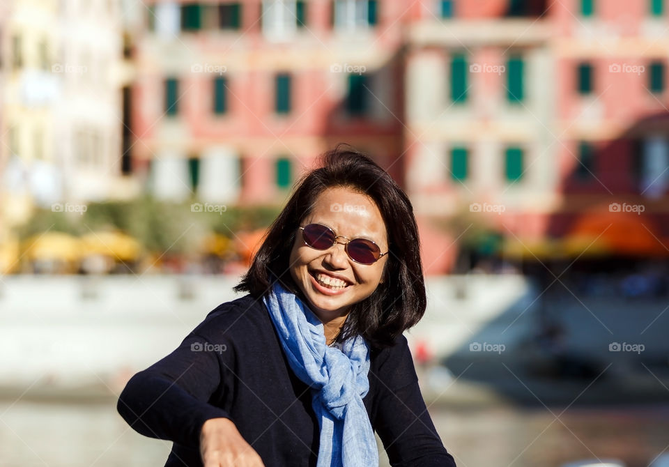 Smiling young woman sitting in front building