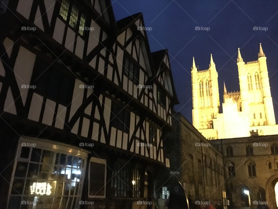 16th century Leigh-Pemberton House timber framed building in the foreground (tourist information centre) and Lincoln cathedral in the background lit up at night