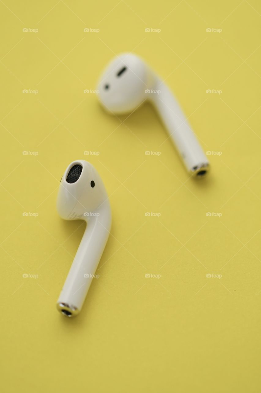 Photo of wireless earphones on yellow background