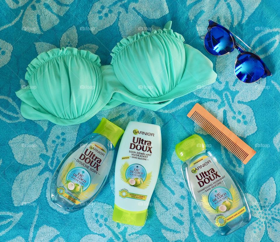 Garnier eau de coco shampoo conditioner and bath gel on a blue towel with comb and bikini.