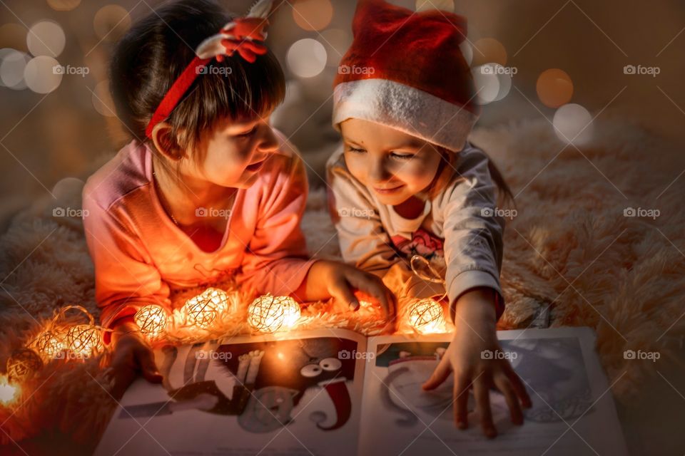 Little sisters reading a book at Christmas time 