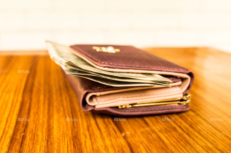 Indian five hundred (500) rupee cash note in brown color wallet leather purse on a wooden table. Business finance economy concept. Side angel view with copy space room for text on left side of image.