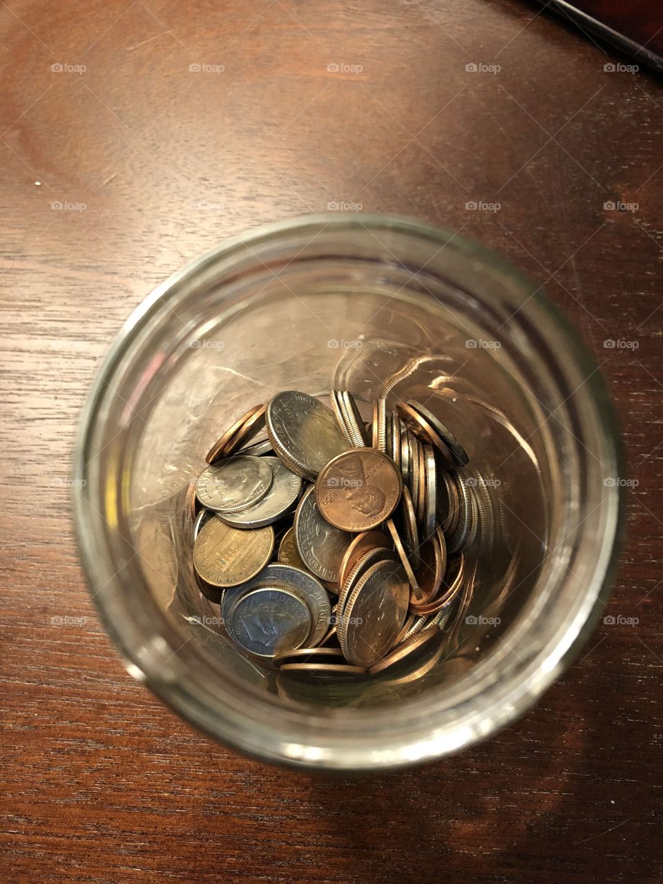Saving money little by little by stashing pocket change in a jar. Every penny counts.