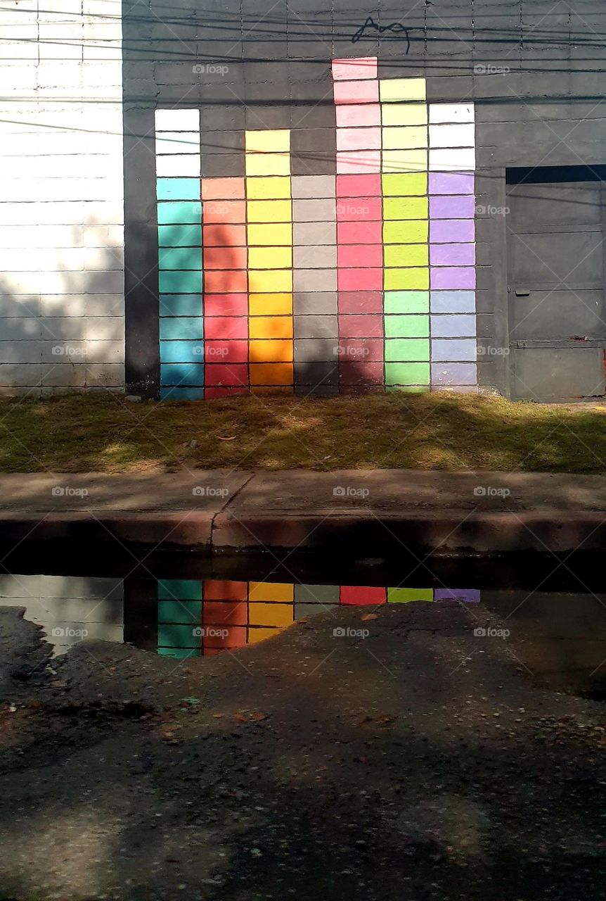 Passing the street to get to the shade of the trees on the other side where there is a flashing mural flashy colors