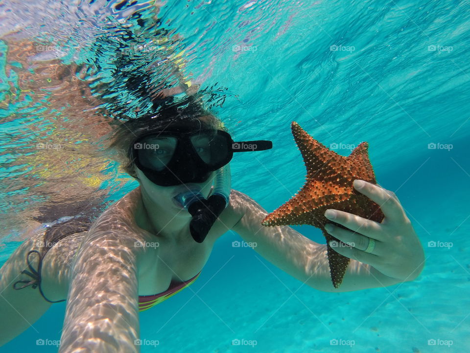Female scuba diver holding starfish in hand