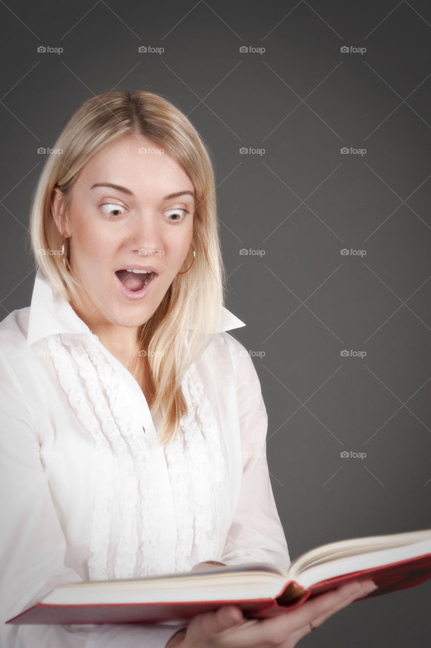 The girl has opened a mouth from astonishment. Studio. Isolated on a gray background.