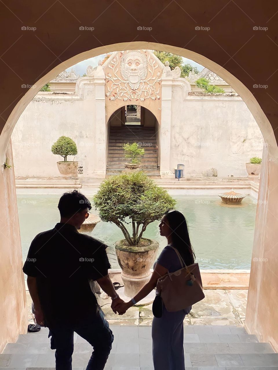 Portrait of a young couple holding hands in front of the swimming pool at a historical tourist attraction