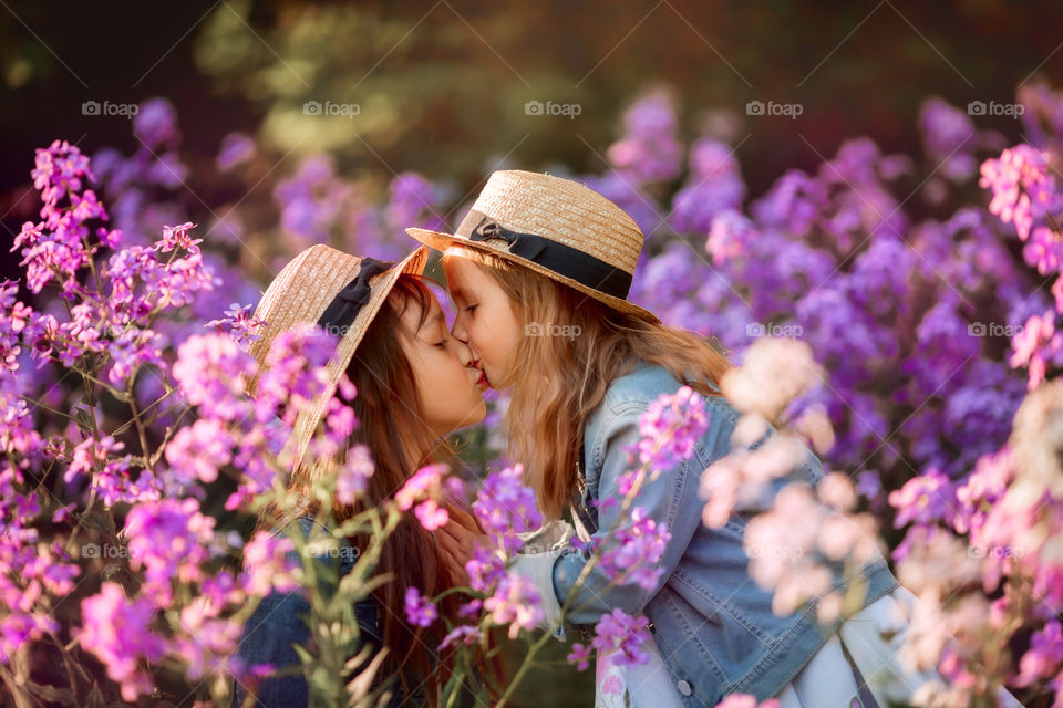 Little sisters in a blossom meadow at sunset 