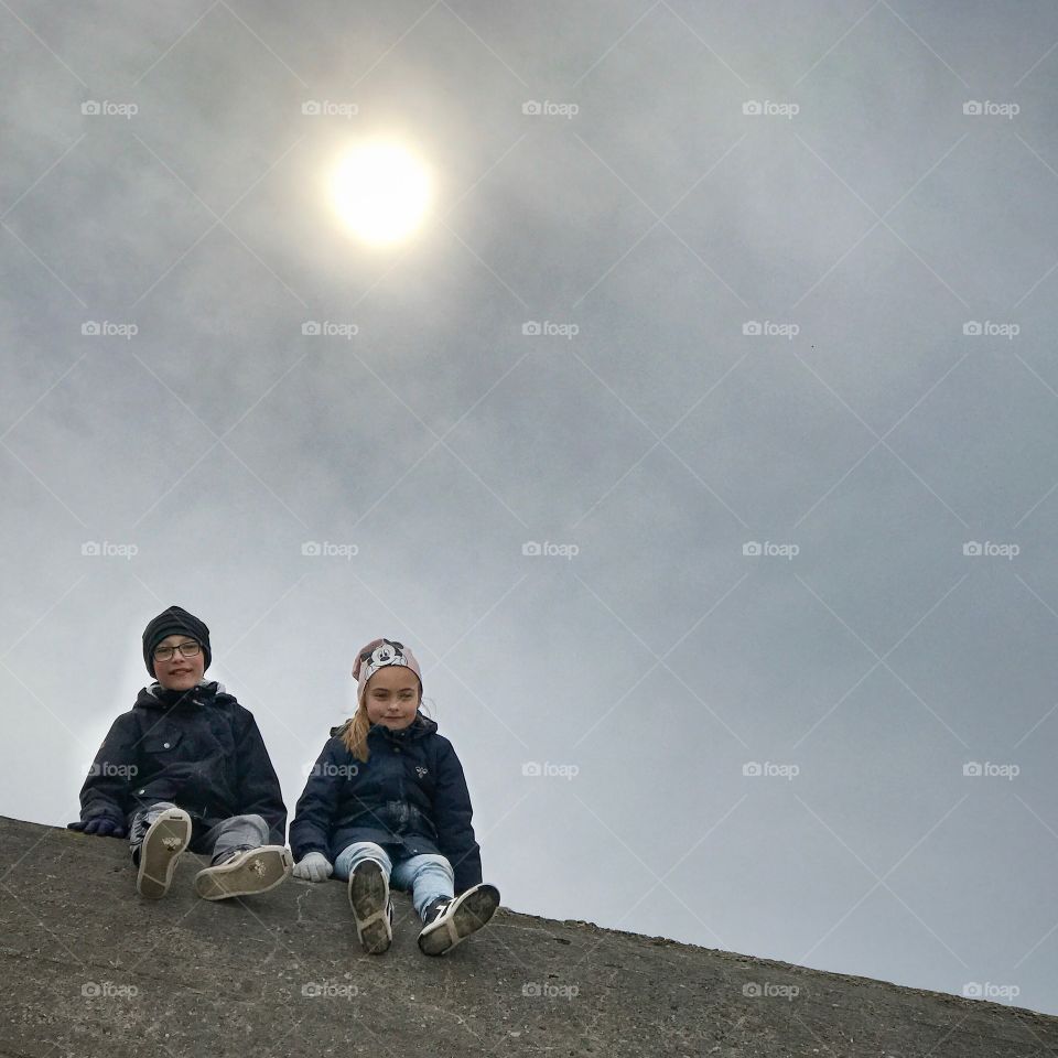 Two kids sitting on top of a world war II relic.... an old bunker on the danish north westcoast. 