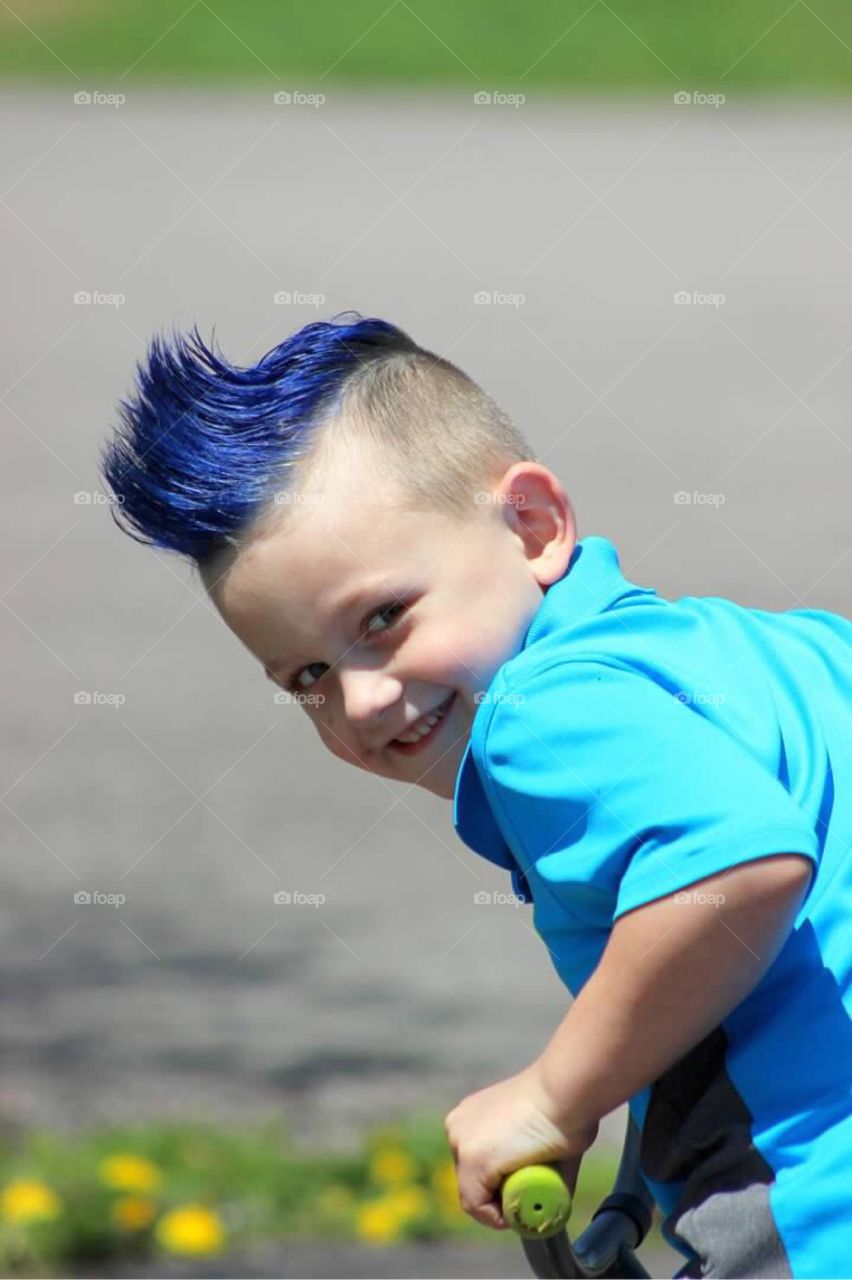 My little boy with a bright blue mohawk with a very mischievous grin on his face. 