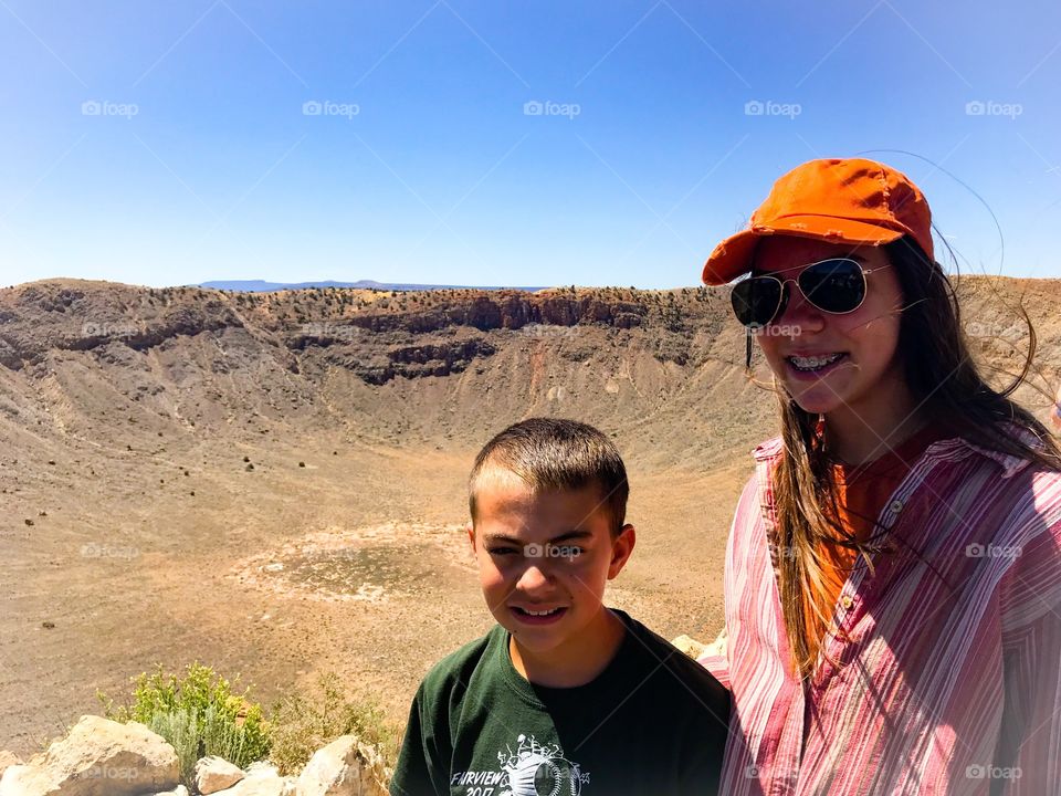 Two cute adolescents with a meteor crater in background