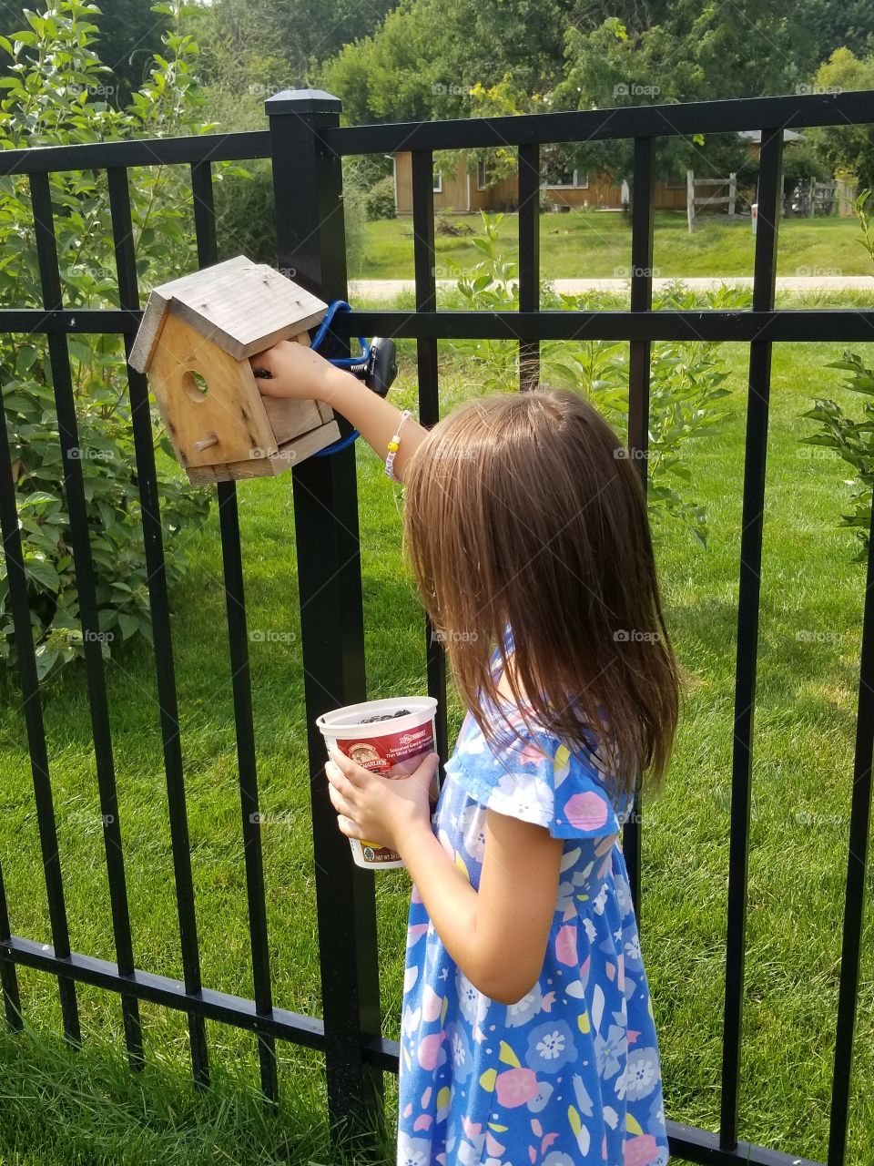 girl refilling bird feeder