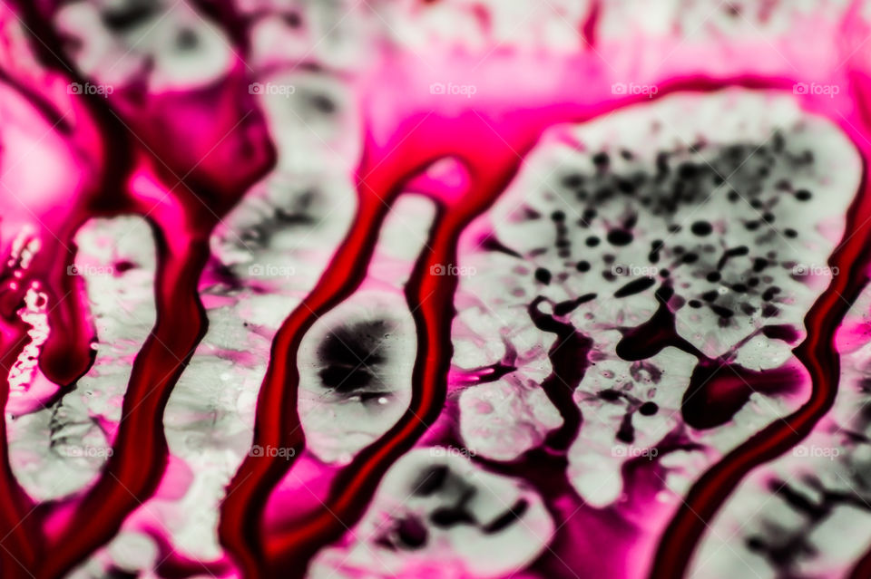 Black and pink refill ink spilled onto the white sink and the ink mixed into abstract blobs and patterns.