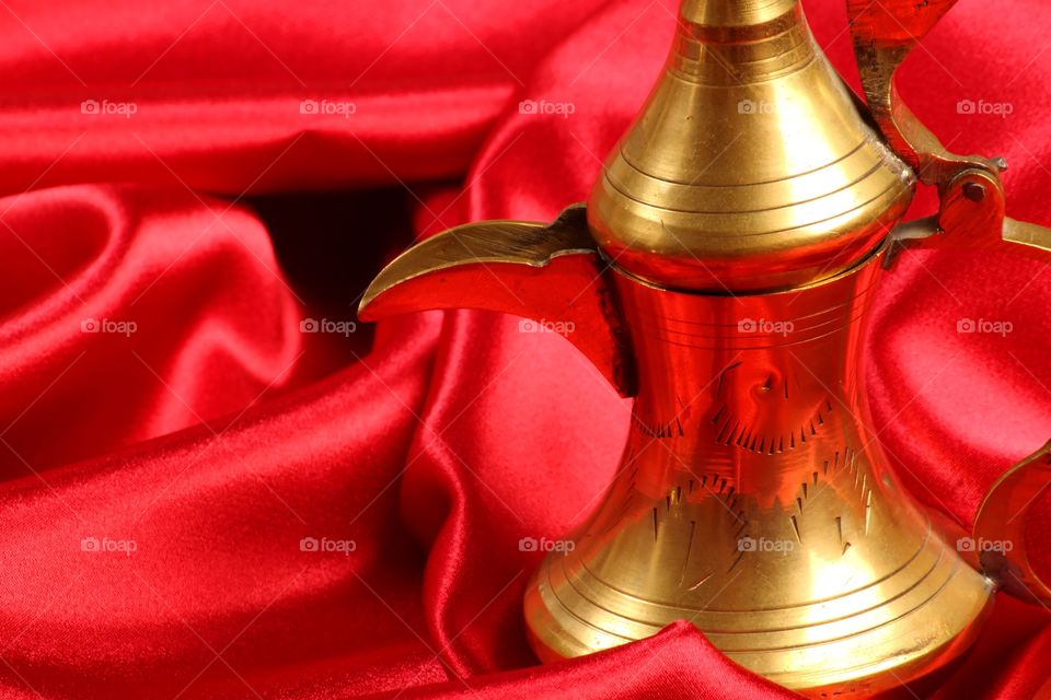 Middle eastern coffee pot Dallah on red satin background