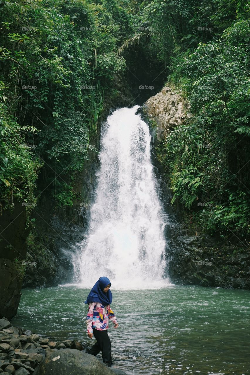 A girl spends her time by having holiday in the waterfall