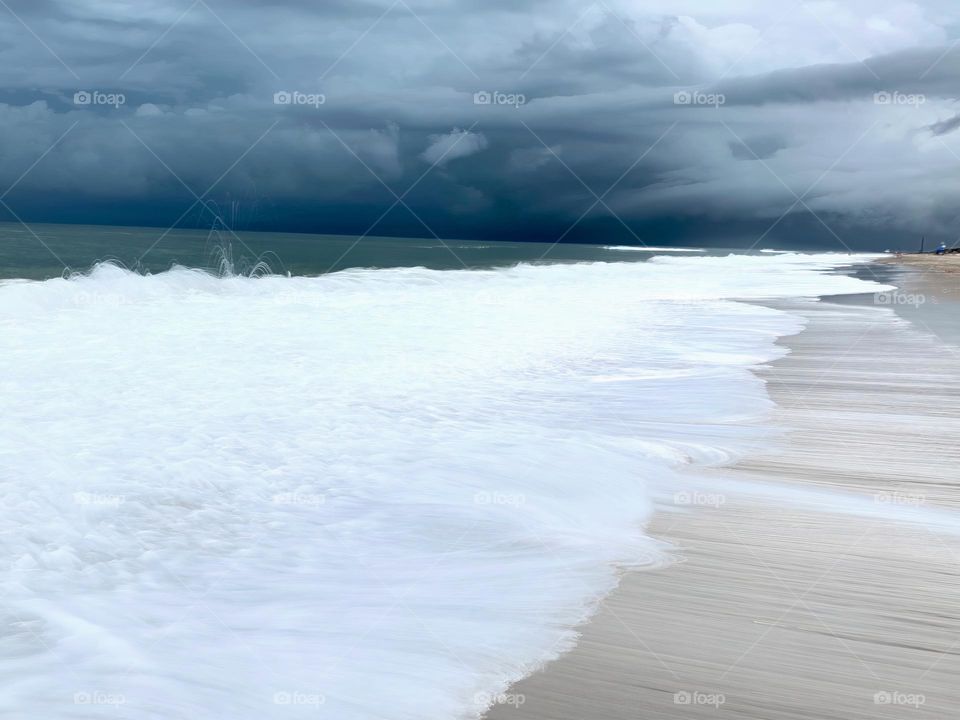 Atlantic Ocean Beach With Time In Motion Long Exposure Of The Waves On The Seashore During A Thunderstorm With Dark Grey Clouds.