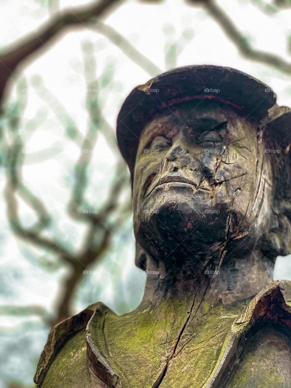 Wooden man carving aged in moss trees in background