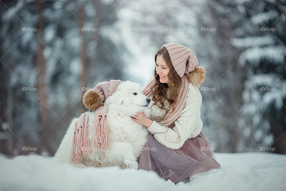 Beautiful woman with dog samoyed in winter forest