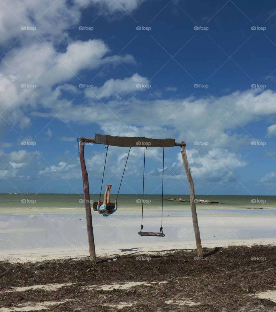 girl on a swing on a lonely paradise beach in the caribbean sea
