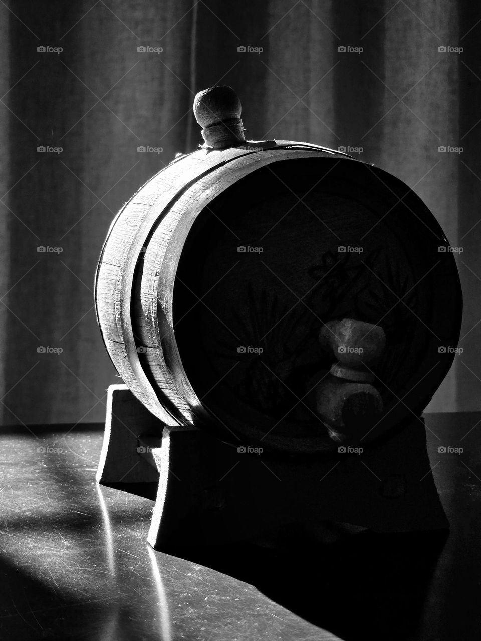 Beer barrel on a dark table while the sunlight illuminated it, taken in monochrome style.