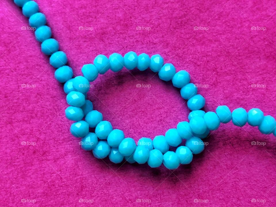 Knot of turquoise beads on pink paper