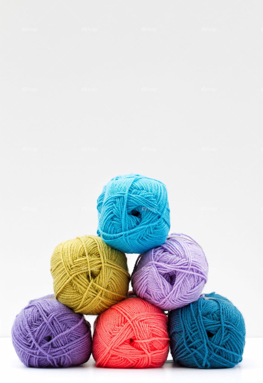 Balls of wool in a pile on a white background.