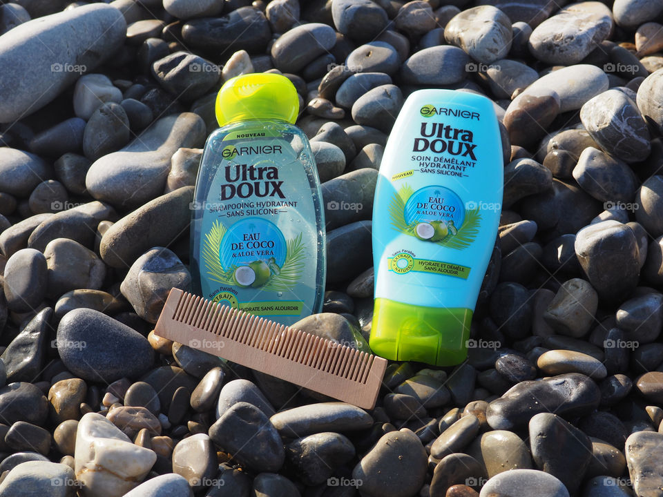 Garnier eau de coco with wood comb on beach stones.