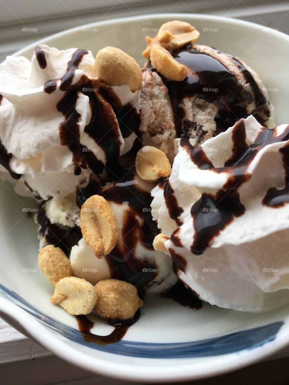 Chocolate drizzled over ice cream whip cream and peanuts. 